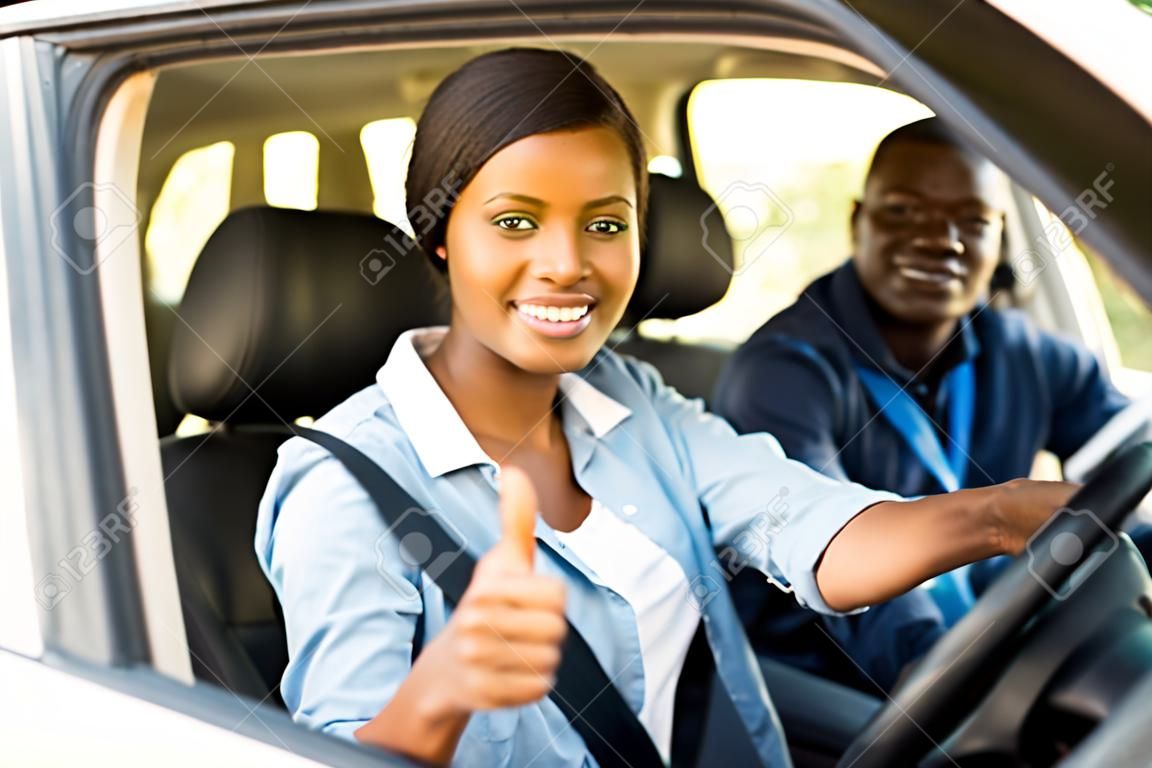 與導師給豎起大拇指美麗的非洲女性學習駕駛