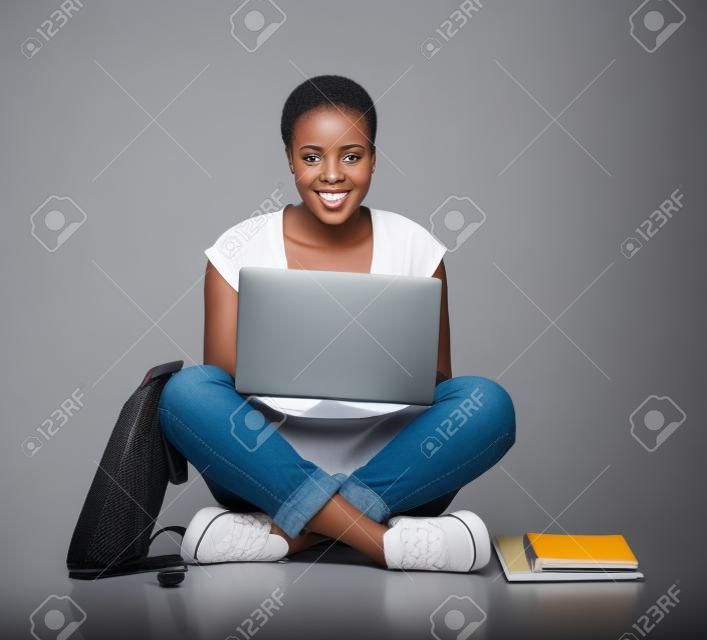 attractive femme étudiant africain utilisant un ordinateur portable isolé sur fond blanc