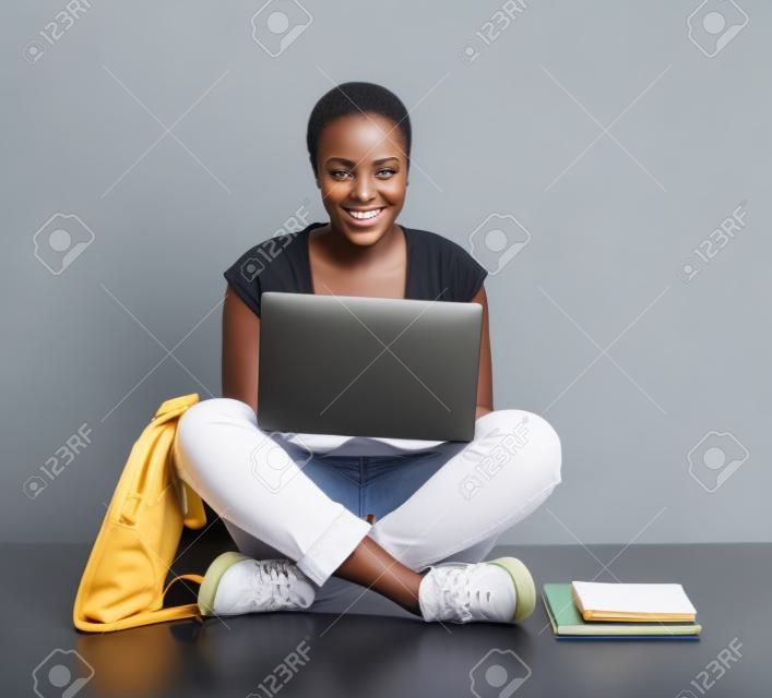 hembra atractiva estudiante Africana usando la computadora portátil aislados en fondo blanco