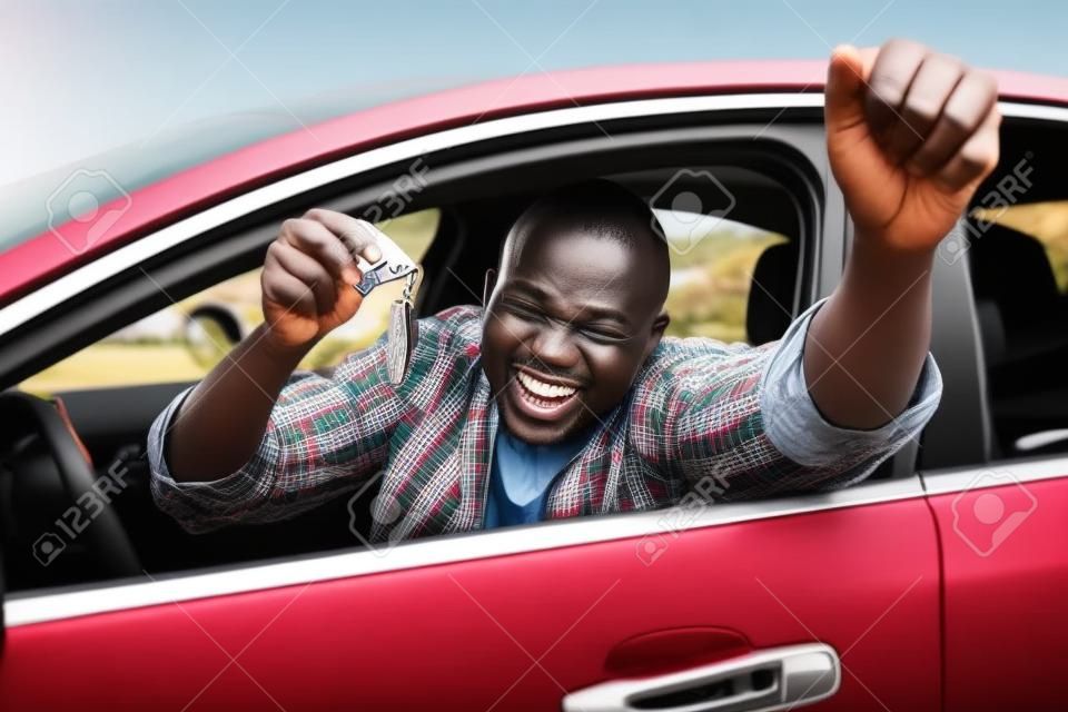 podekscytowany african człowiek pokazano kluczyk wewnątrz swojego nowego pojazdu