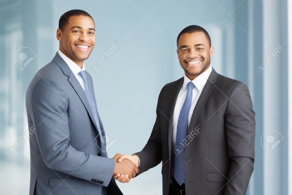 Retrato de la feliz americano apretón de manos hombres de negocios africano