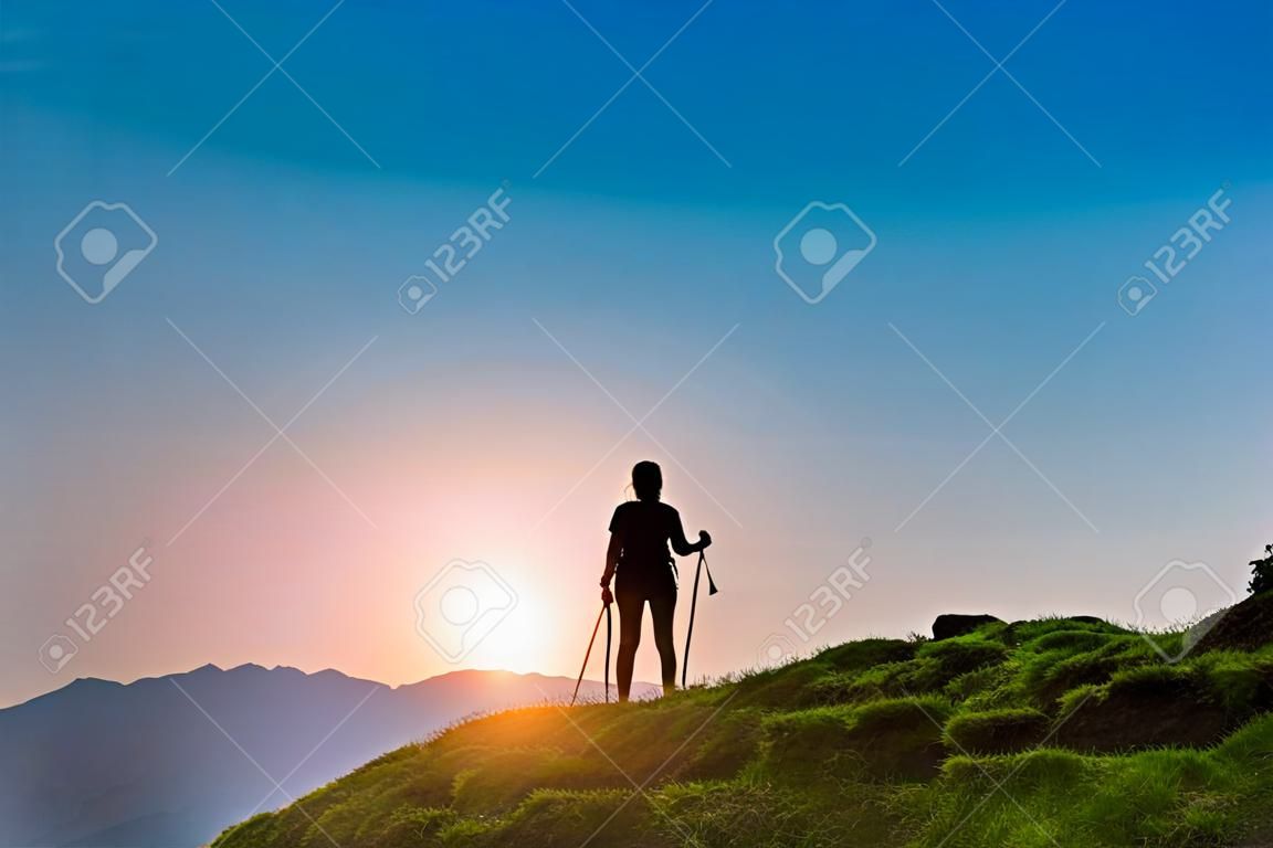 Silhouette d'une fille qui fait du trekking au coucher du soleil