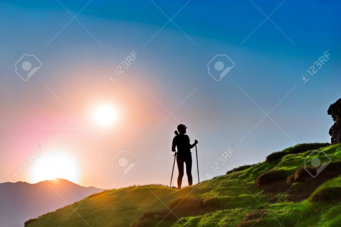 Silhouette d'une fille qui fait du trekking au coucher du soleil