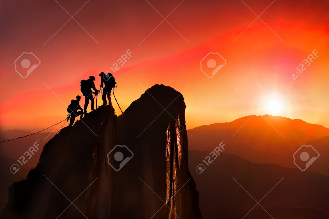 Equipe de alpinistas ajudam a conquistar o cume em trabalho de equipe em uma fantástica paisagem montanhosa ao pôr do sol