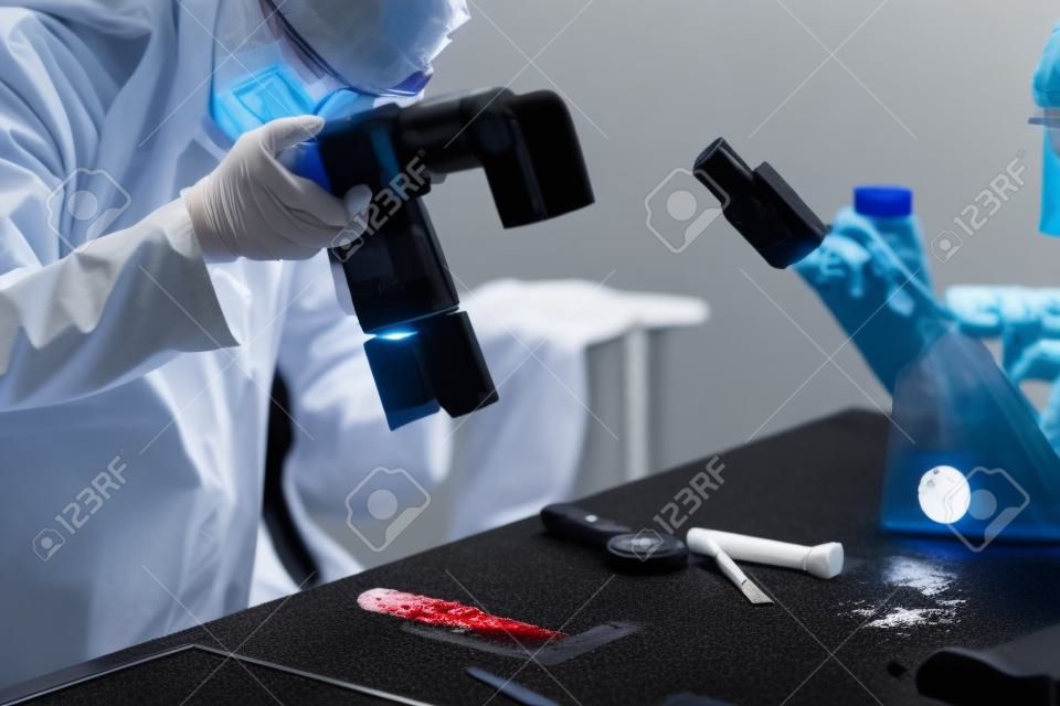 Forensic Science in Lab. Forensic Scientist photographing knife with blood evidences