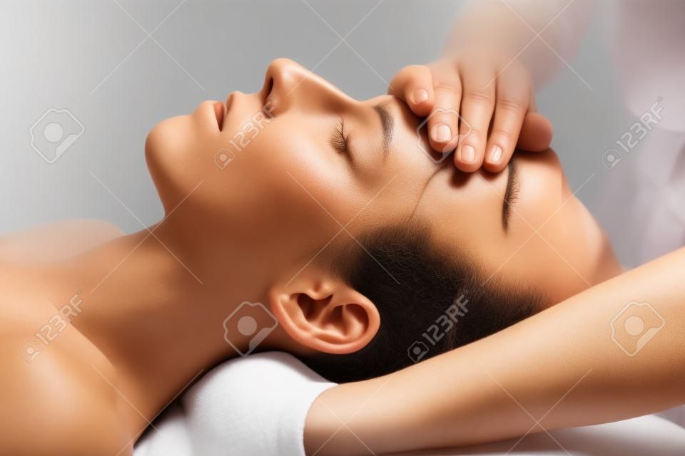 頭蓋仙骨療法マッサージ。女性の額をマッサージするセラピスト。