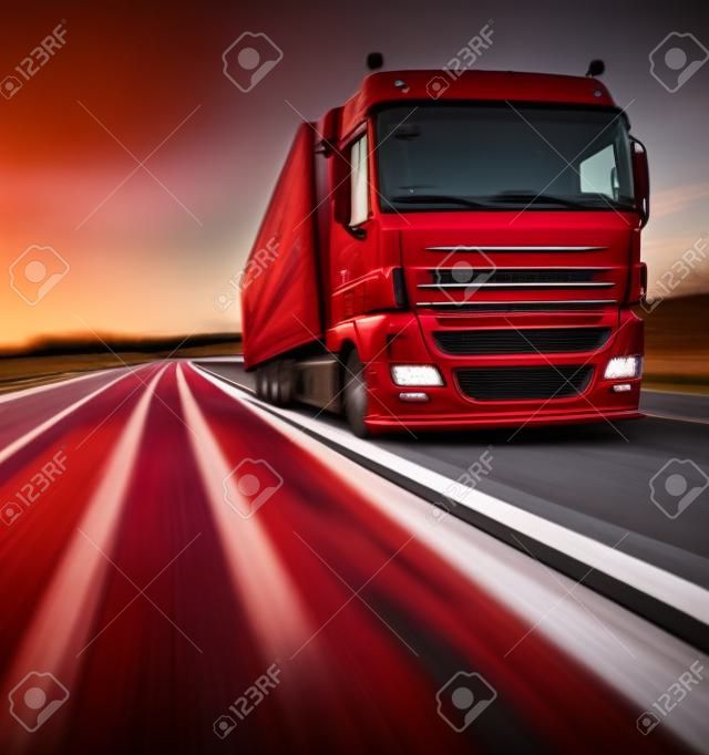 Red truck on blurry asphalt road and motion blured sky