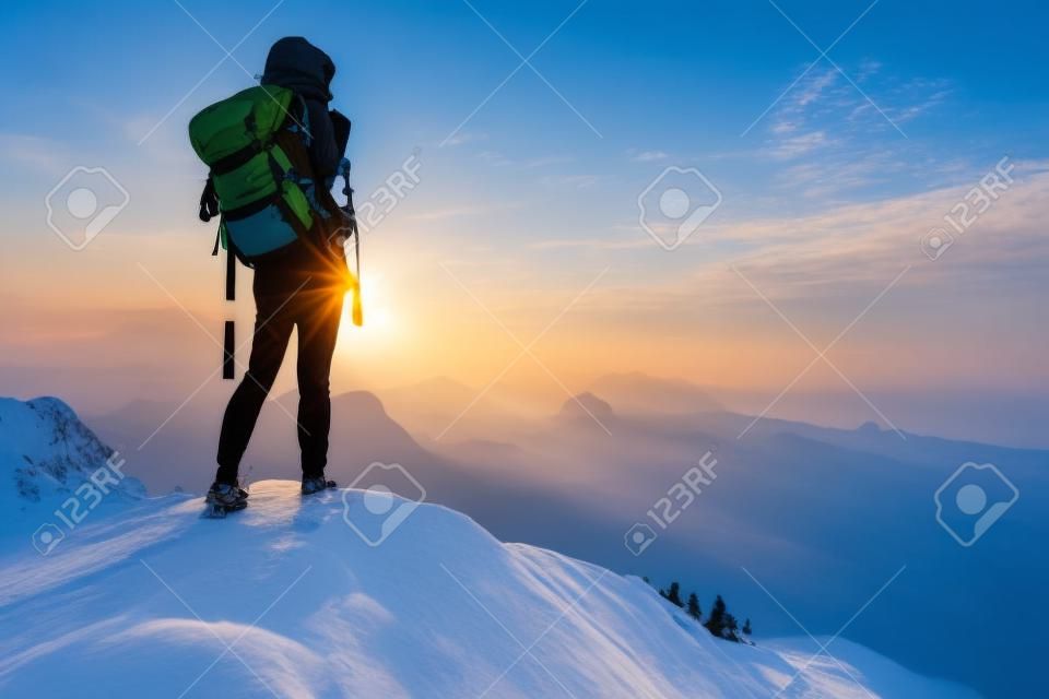 Turysta z plecakiem, relaks na szczycie góry i cieszyć widokiem na dolinę podczas wschodu słońca