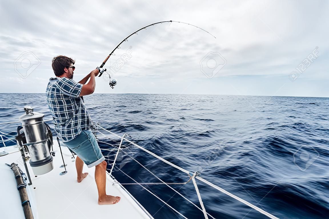 Fiatal férfi halászat nehéz a nyílt tengeren vitorlás