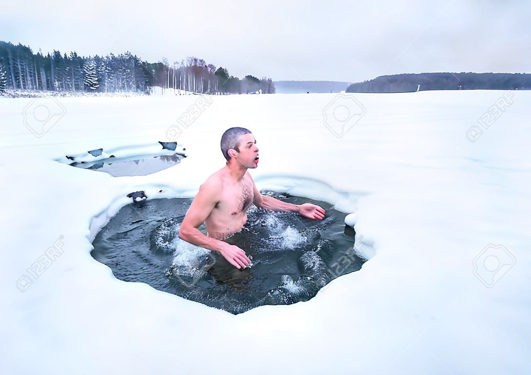 Joven tiene invierno recreativo nadar en el lago