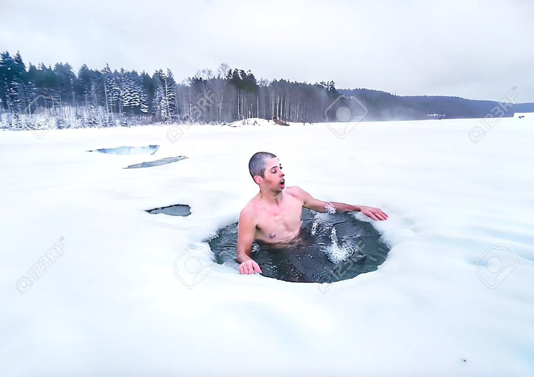Young man haves recreational winter swim in the lake