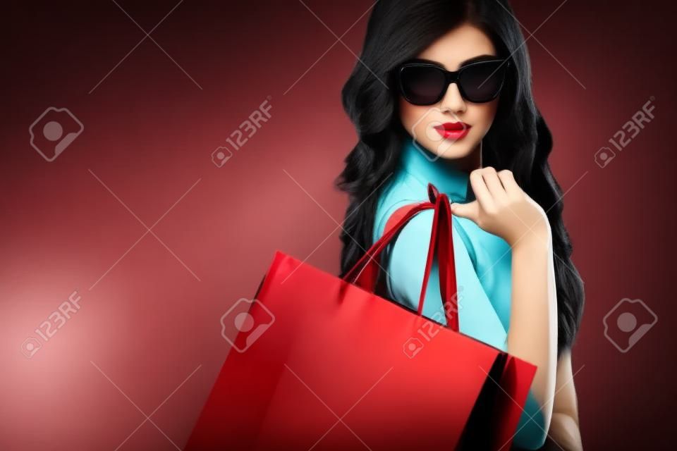 美しい若い女性は、黒い金曜日の休日のショッピングを確認します。暗い背景に黒いバッグを持つ少女。