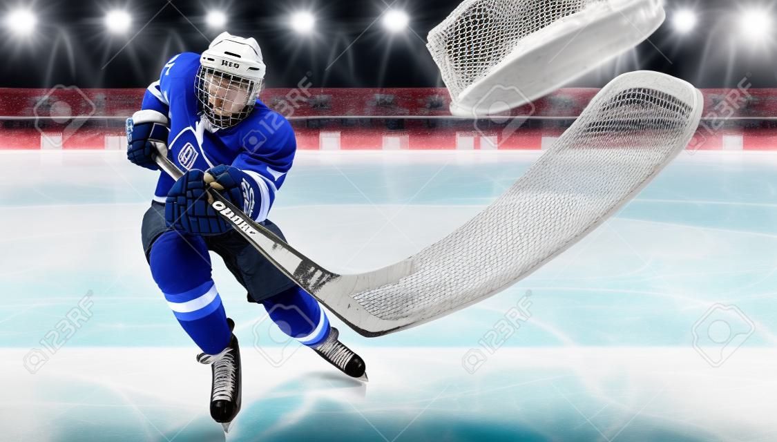 Athlète joueur de hockey sur glace dans le casque et les gants sur le stade avec bâton. Tir d'action. Notion sportive.