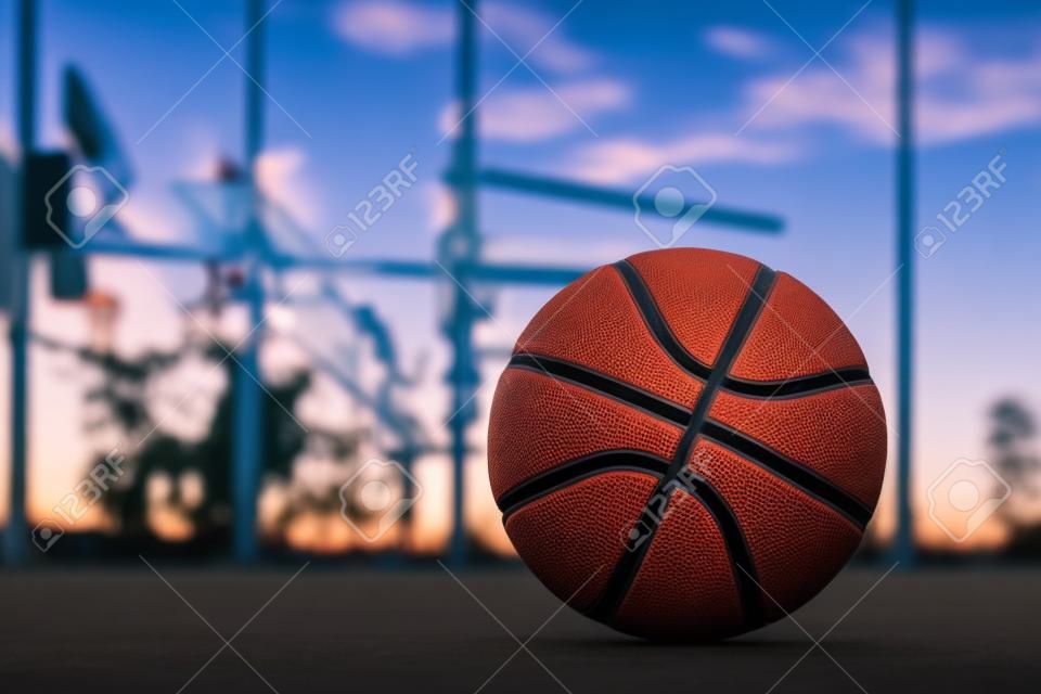 Basketball liegt auf dem Boden vor dem Hintergrund des Abendhimmels. Sportlicher Hintergrund