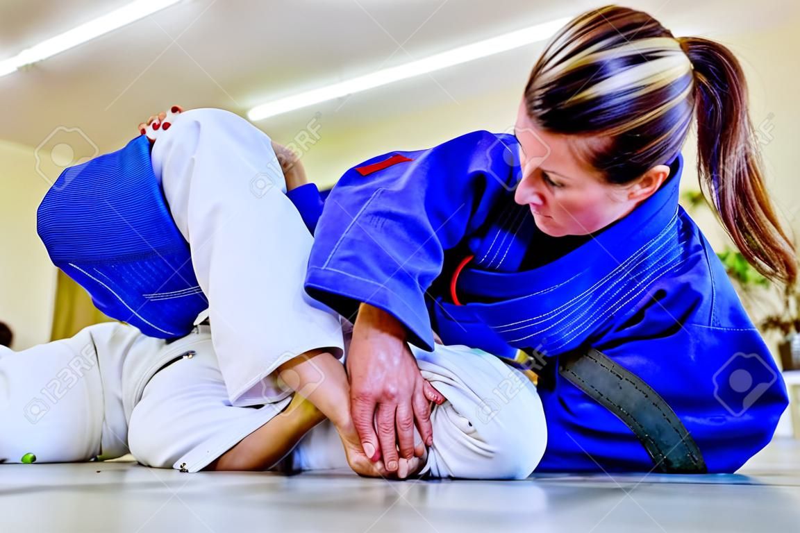 Vrouw in Braziliaanse jiu jitsu bjj training judo kimura aanval arm slot van de wacht positie onderwerping attemp