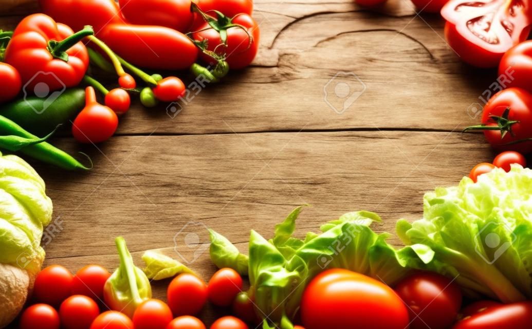 Rahmen von frischem Bio-Gemüse auf Holz Hintergrund. Gesunde natürliche Lebensmittel auf rustikalen Holztisch mit Kopie Raum. Tomaten, Salat und andere Zutaten zum Kochen Draufsicht, weich Tonung