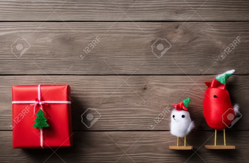 Sfondo di Natale con spazio di copia. Vista dall'alto di scatole regalo e giocattoli uccelli divertenti. Presenta in carta del mestiere con fiocchi di nastro rosso e albero di abete rosso su legno bianco. Celebrazione del concetto di vacanze invernali