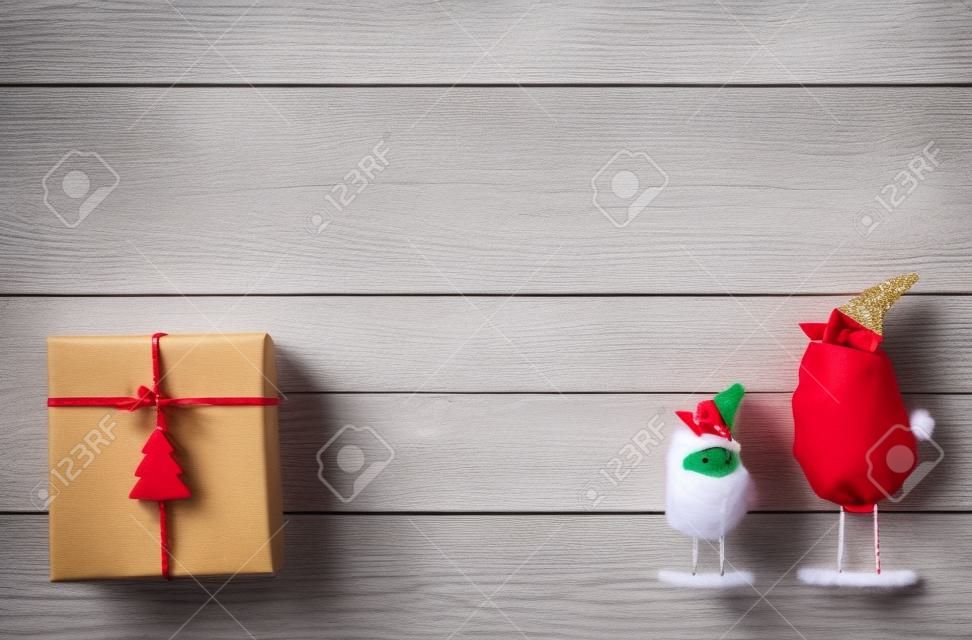 Christmas background with copy space. Top view of gift boxes and funny birds toys. Presents in craft paper with red ribbon bows and spruce tree on white wood. Celebration of winter holidays concept