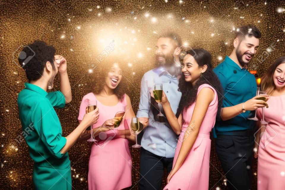 Festa de Natal do escritório. Grupo de colegas alegres que se divertem na celebração do ano novo. Jovens sorridentes felizes que bebem champanhe e apreciam a vida.