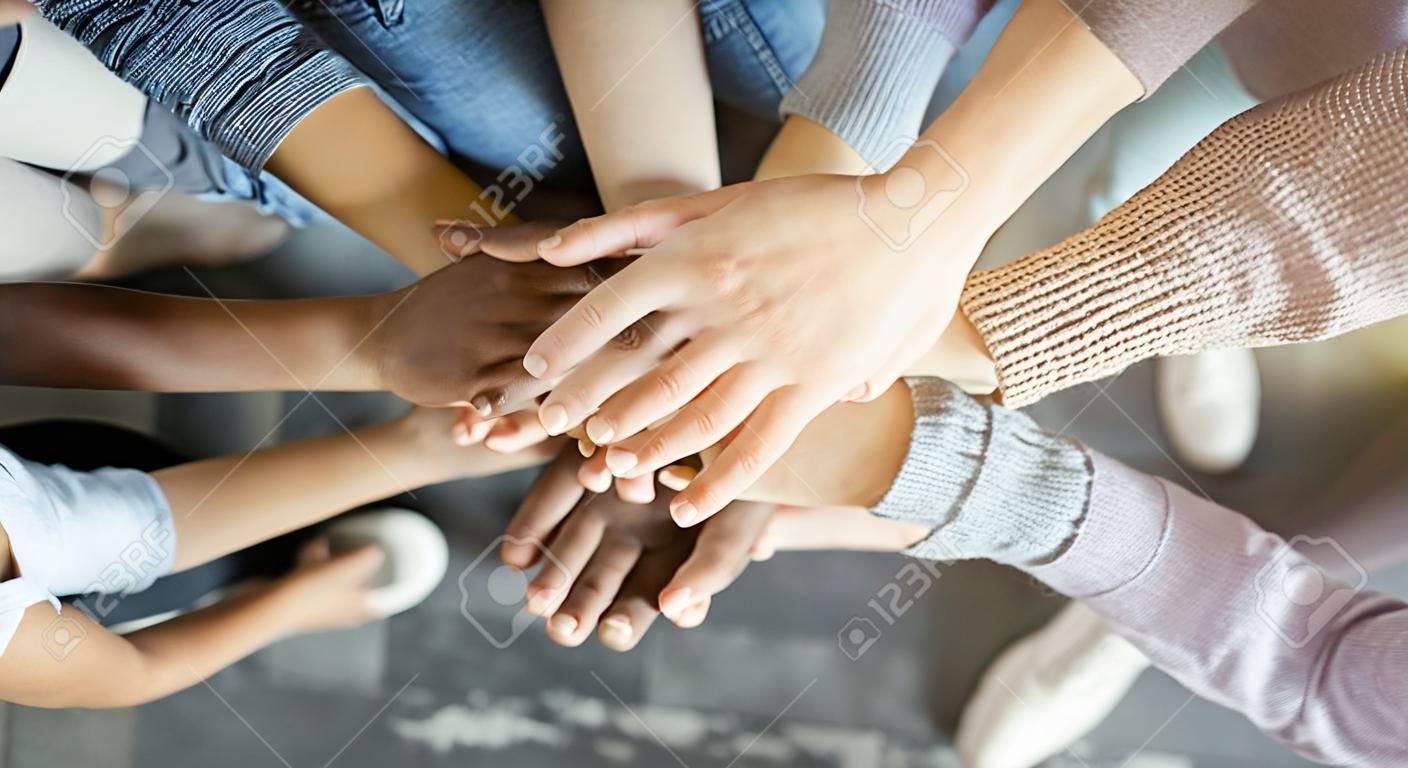 Friendship and teamwork. Multiethnic company of friends stacked hands together, top view, copy space