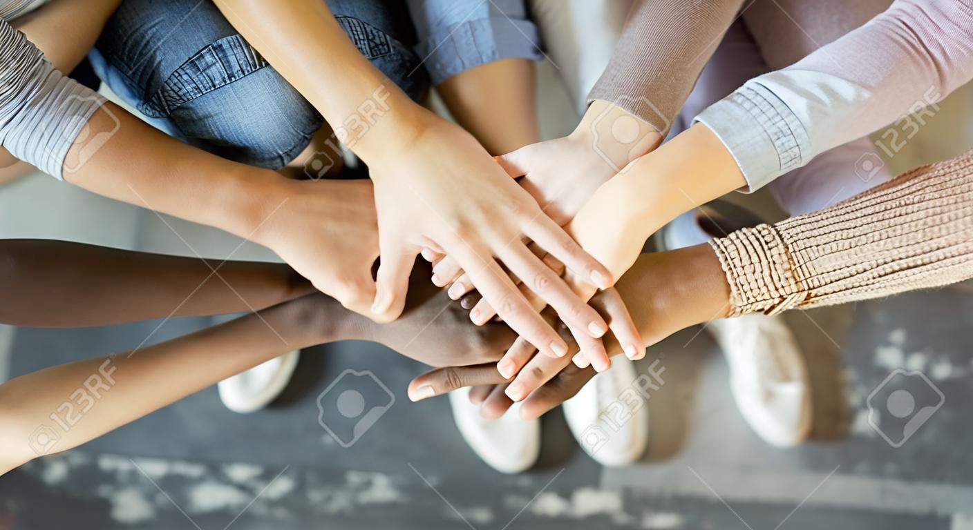 Vriendschap en teamwork. Multi-etnische gezelschap van vrienden stapelde handen samen, top weergave, kopieer ruimte
