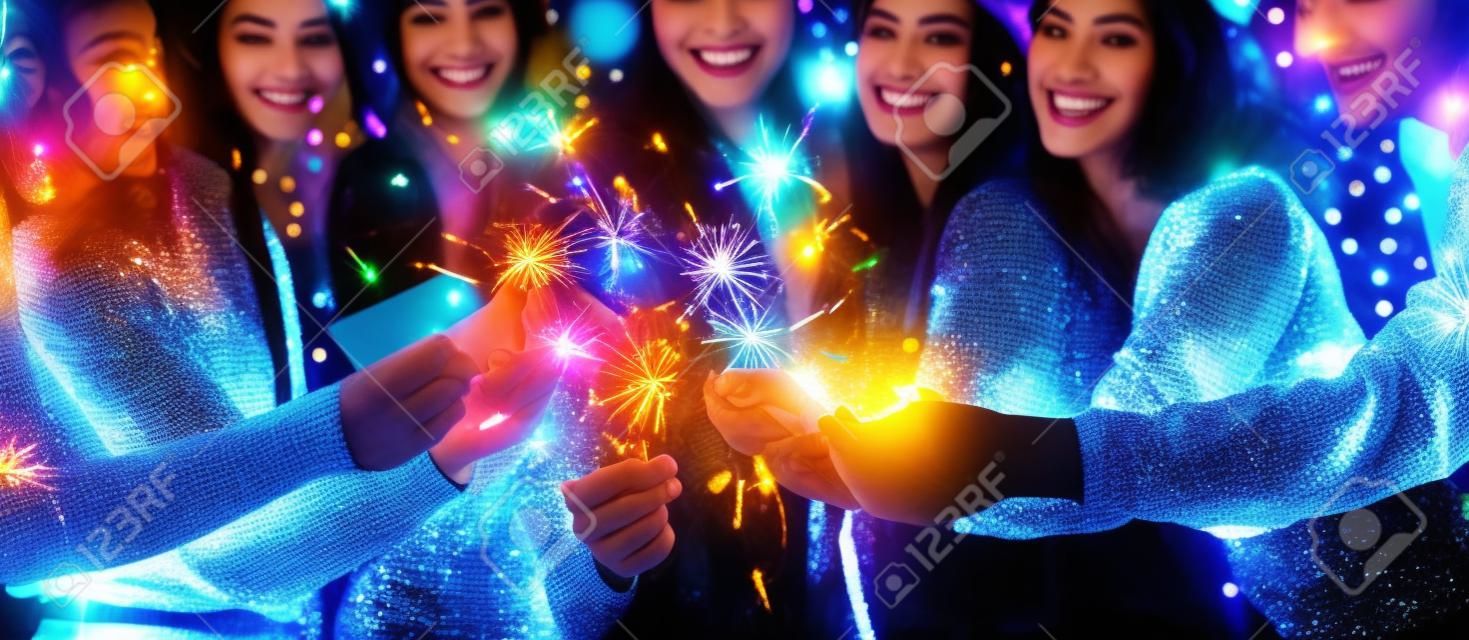 Groep van gelukkige vrienden in Nieuwjaarsavond met sprankelende bengaalse verlichting, panorama, close-up