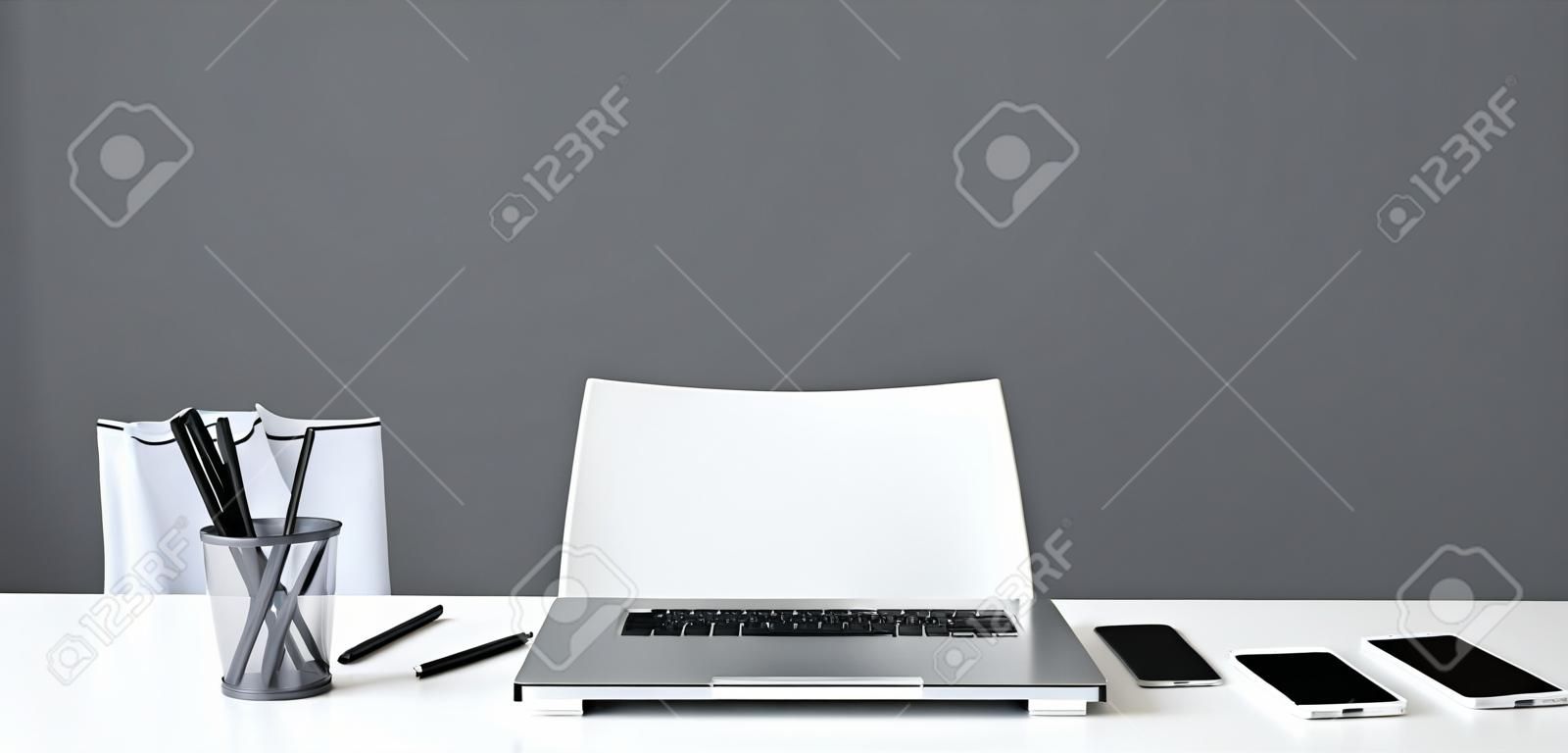 Office table with laptop and chair on grey background. Creative space concept