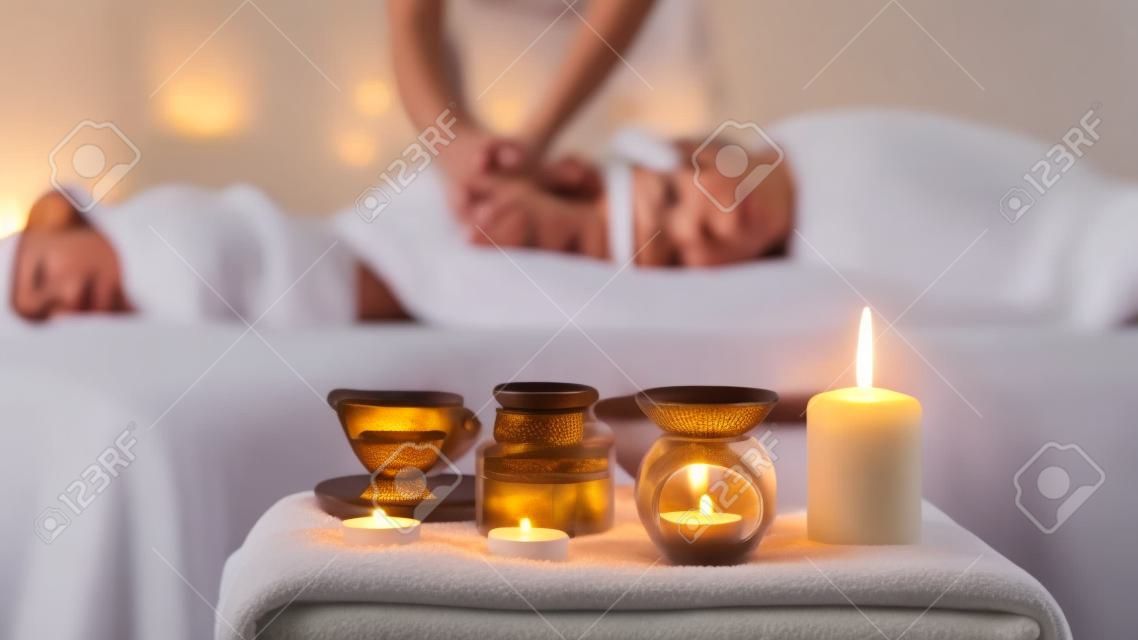 Relaxed woman enjoying aromatherapy massage in luxury spa with candle on foreground