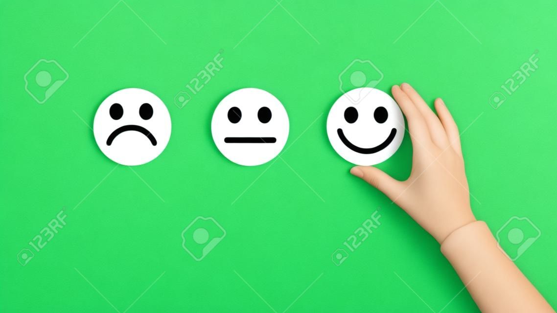 Rating concept. Woman choosing happy smiley face emotion on green background, panorama, copy space