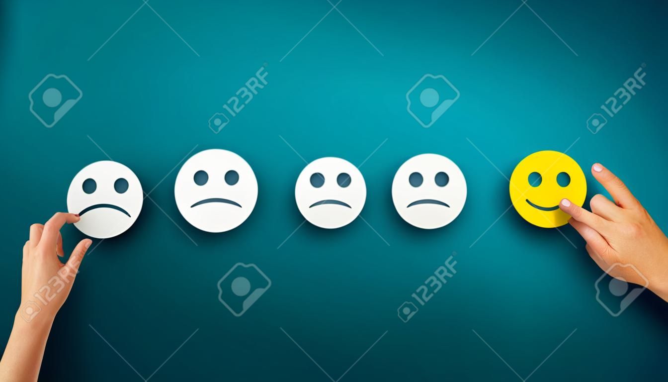 Hand choose the happy smile icon over blue background, panorama, copy space. Customer service evaluation and satisfaction survey concept