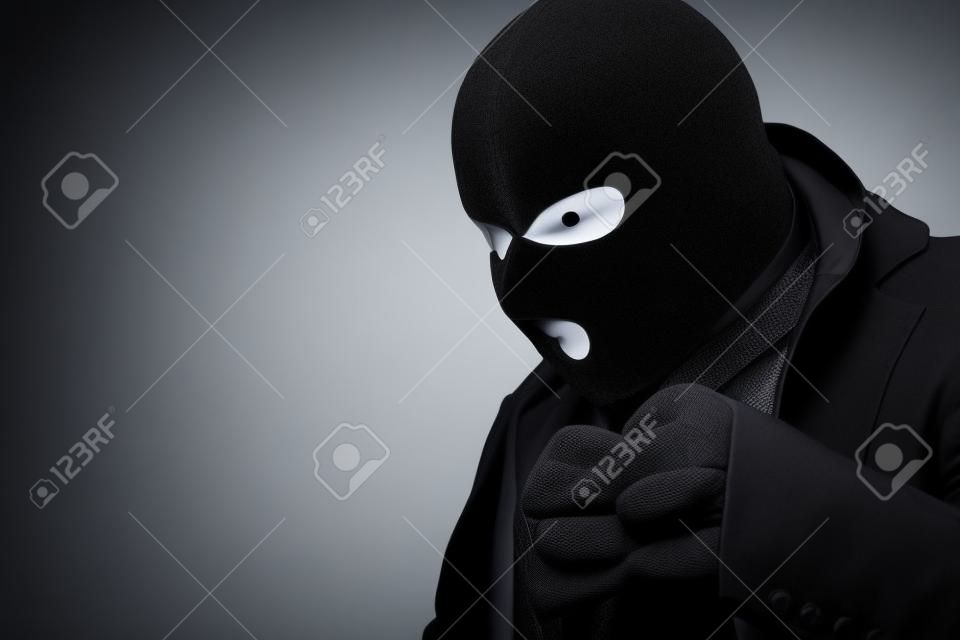 Closeup retrato de ganancioso disfarçado vilão em máscara preta olhando para algo para roubar, copyspace, parede de estúdio branco