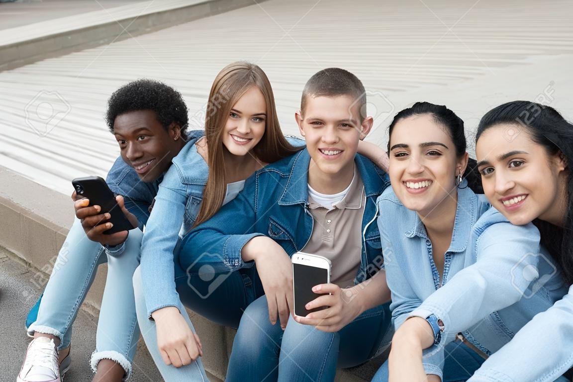Fünf gemischtrassige Freunde, die sich mit dem Telefon im Freien selbst machen