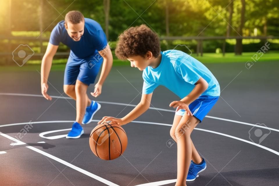 Sportieve vader leert zijn zoon basketbal spelen buiten