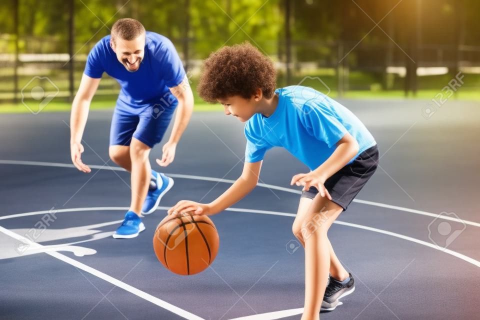 Sportieve vader leert zijn zoon basketbal spelen buiten