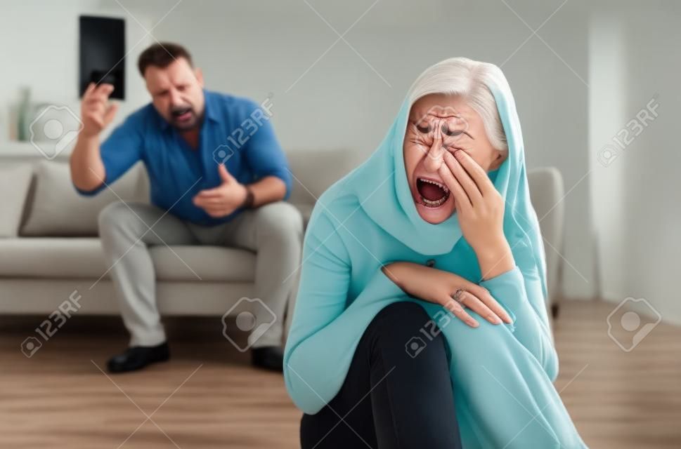 Homme mûr abusant de sa femme déprimée, criant, humiliant et menaçant, femme d'âge moyen pleurant à la maison