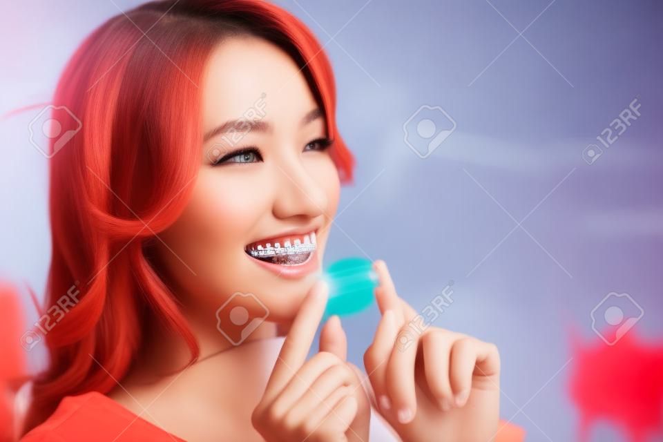 Young attractive woman holding invisible braces or trainer