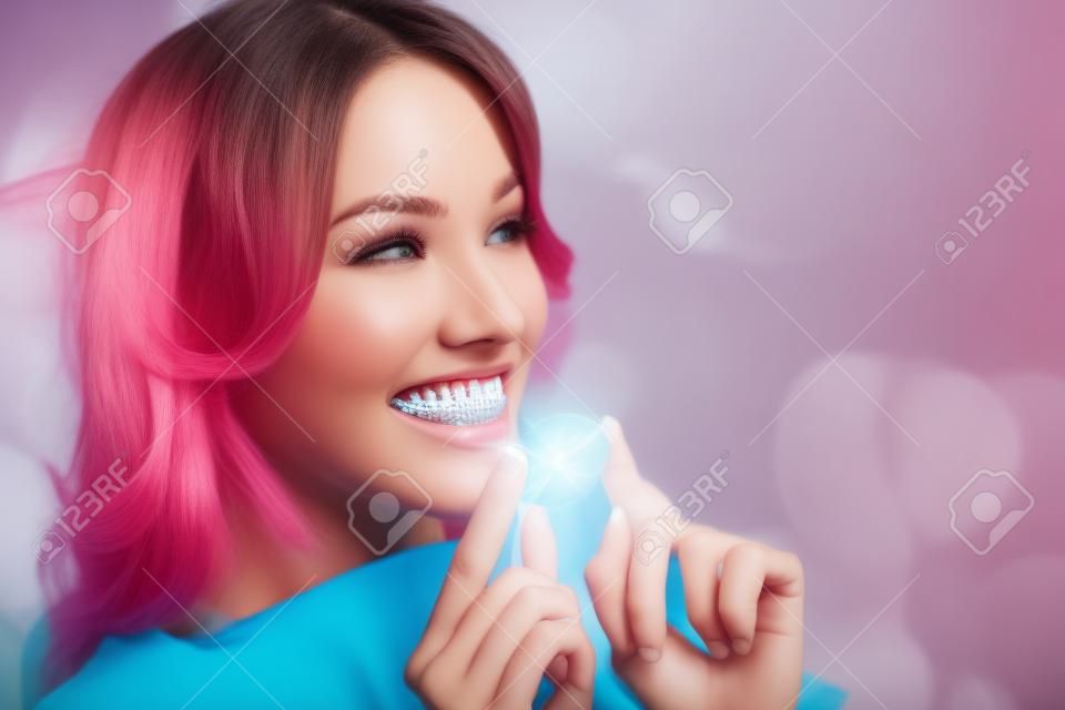 Young attractive woman holding invisible braces or trainer