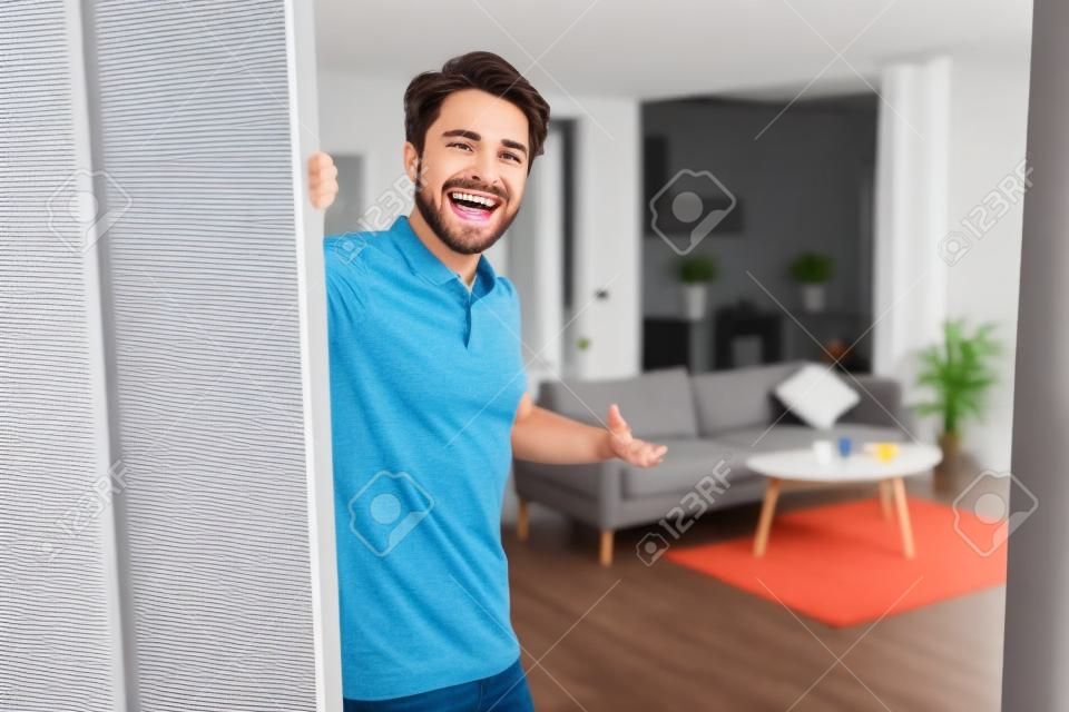 Cheerful guy inviting people to enter home