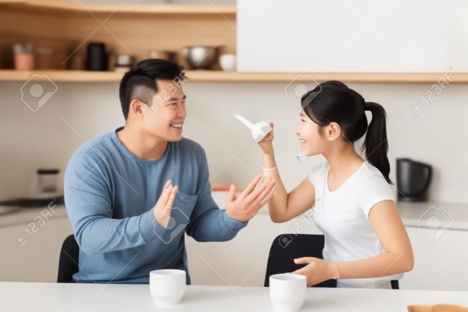 Asian couple arguing while drinking coffee at kitchen