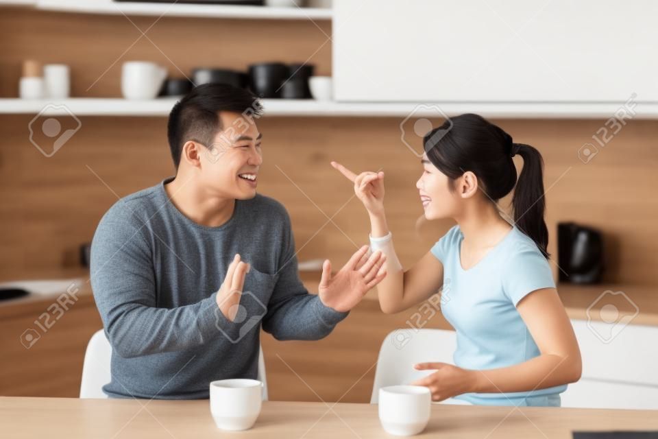 台所でコーヒーを飲みながら議論するアジア人夫婦