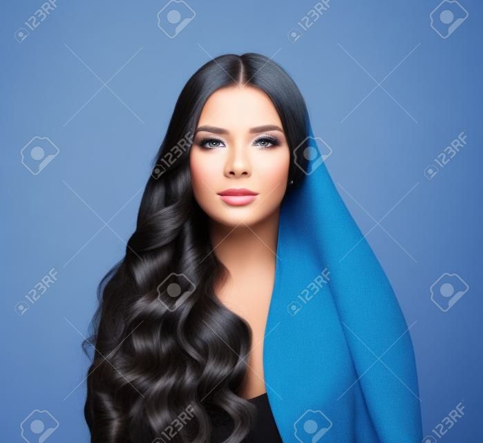 파란 배경에 긴 생머리와 완벽한 곱슬머리를 한 아름다운 패션 모델 여성