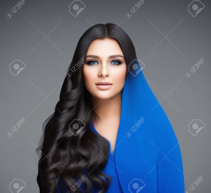 Schöne Mode-Modell-Frau mit langen glatten Haaren und perfekter lockiger Frisur auf blauem Hintergrund