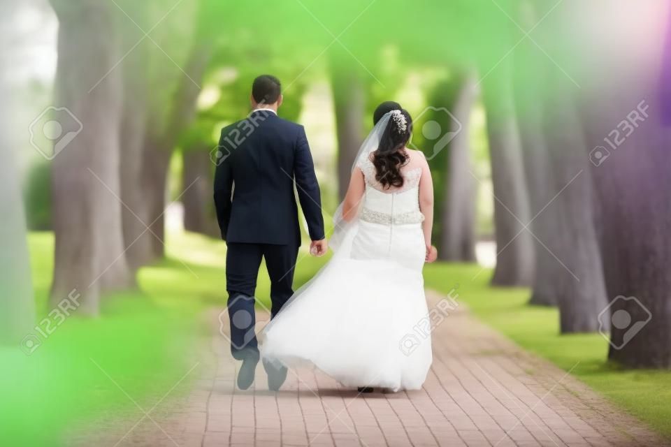 Wedding couple together walking by park alley.