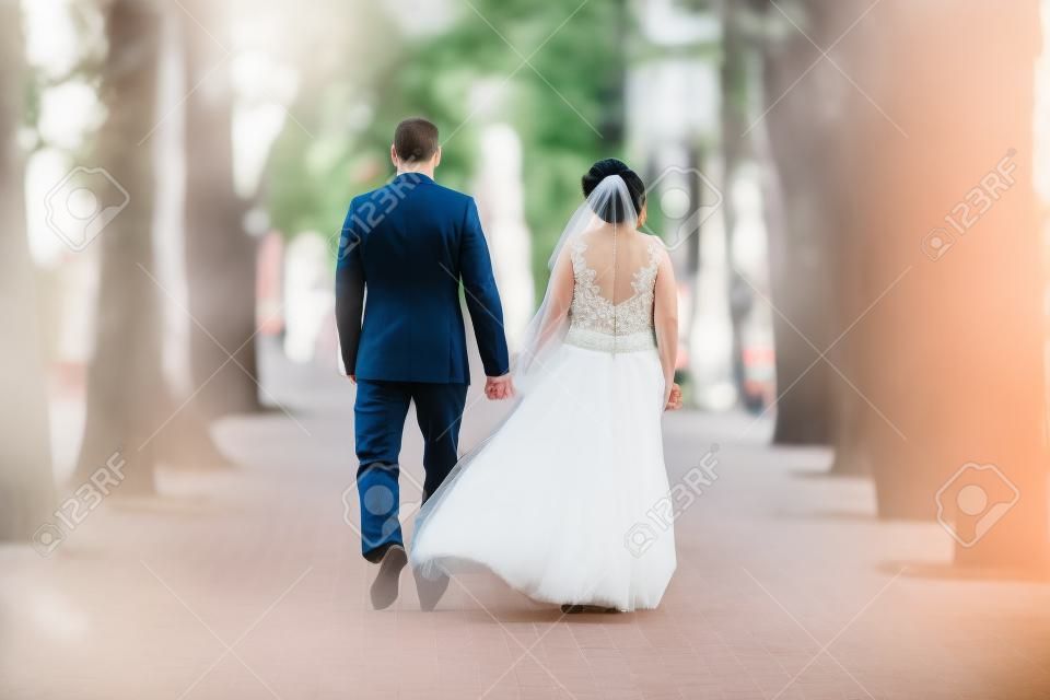 Bruiloft stel samen lopen door het park steegje.