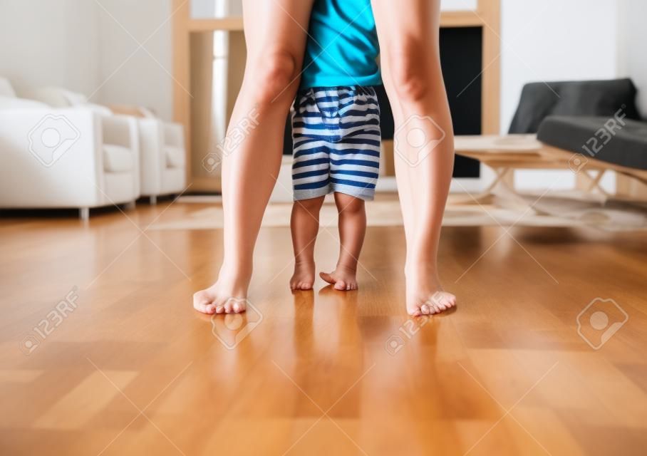 Мать и маленький мальчик, стоя ноги на деревянный пол дома