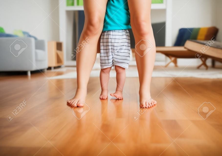 Mother and little boy feet standing on wood floor at home