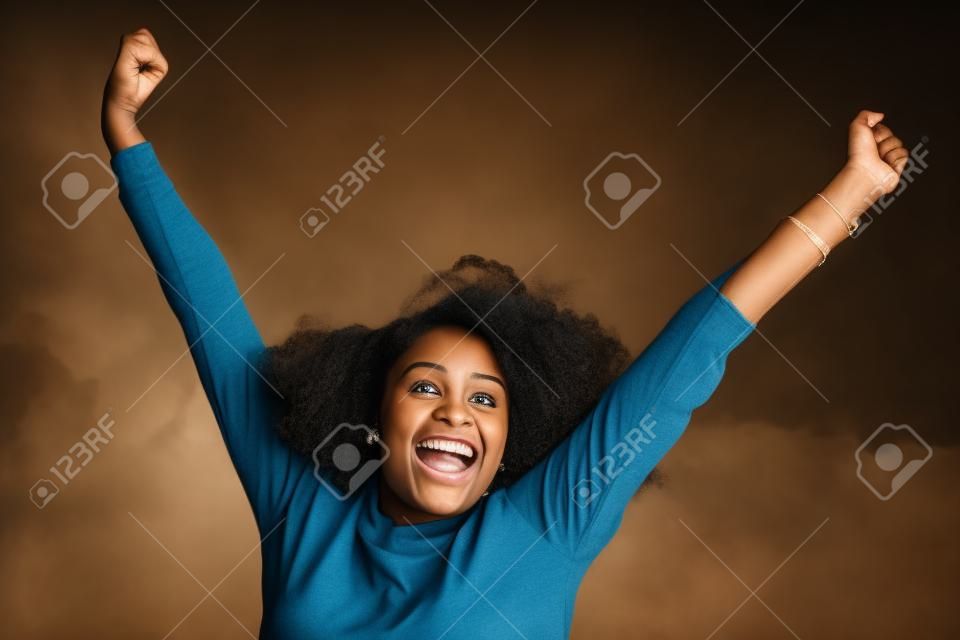 Портрет веселая молодая черная женщина, улыбаясь с поднятыми руками