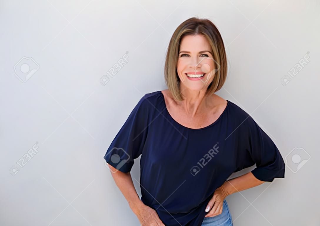 Portrait of senior woman laughing against gray wall