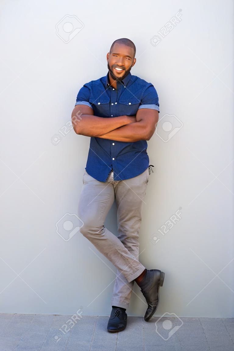 Full length portrait of handsome african american guy smiling with arms crossed
