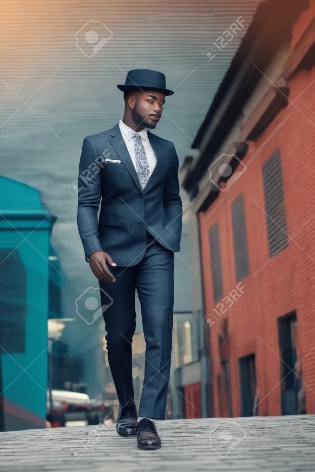 ヴィンテージスーツと街を歩く帽子でアフリカ系アメリカ人の男性モデルの全身肖像画
